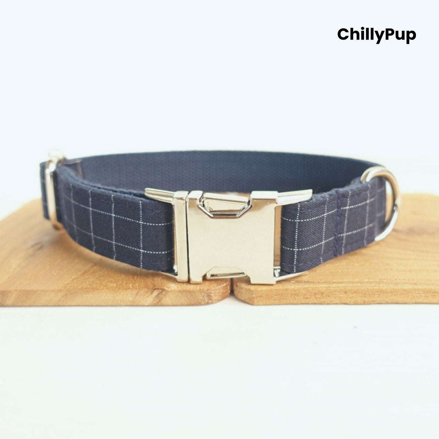 Navy check dog collar with a silver buckle on a wooden block, branded 'ChillyPup'.