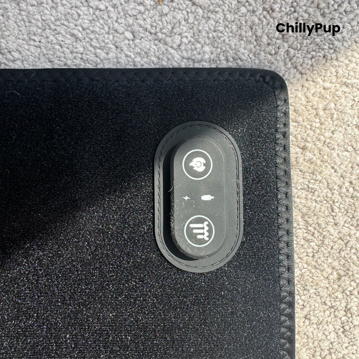 Close-up of a black textured redlight pet mat with a stitched border and an oval control panel featuring white icons, placed on a grey carpet. The ChillyPup brand logo is visible in the top right corner.