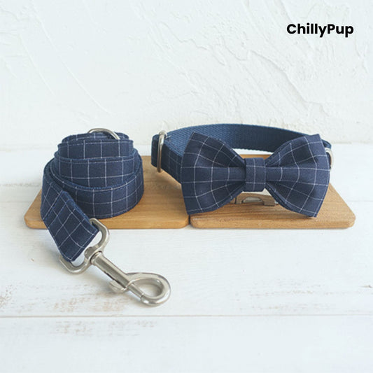 Navy check dog collar with lead and bow with a silver buckle on a wooden block, branded 'ChillyPup'.