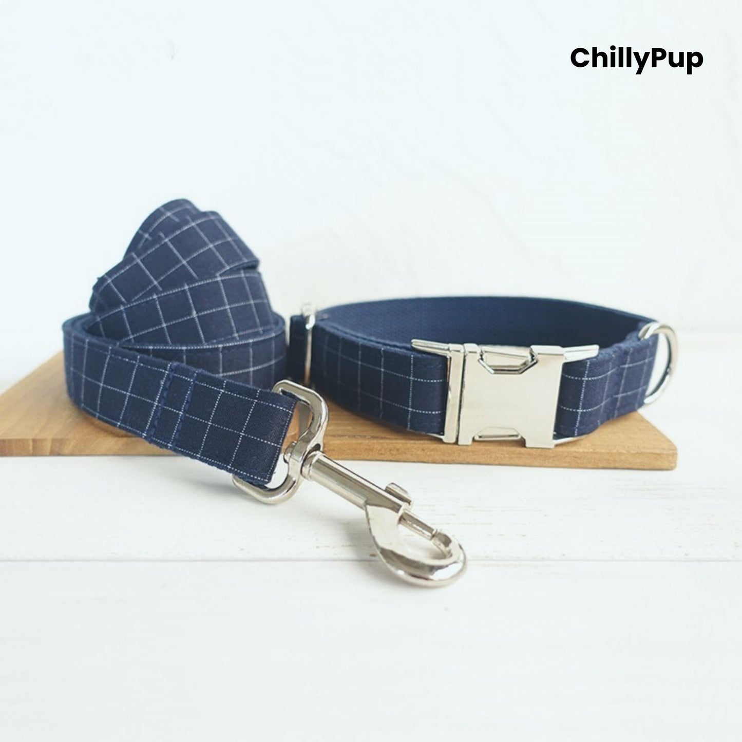 Navy check dog collar and lead with a silver buckle on a wooden block, branded 'ChillyPup'.