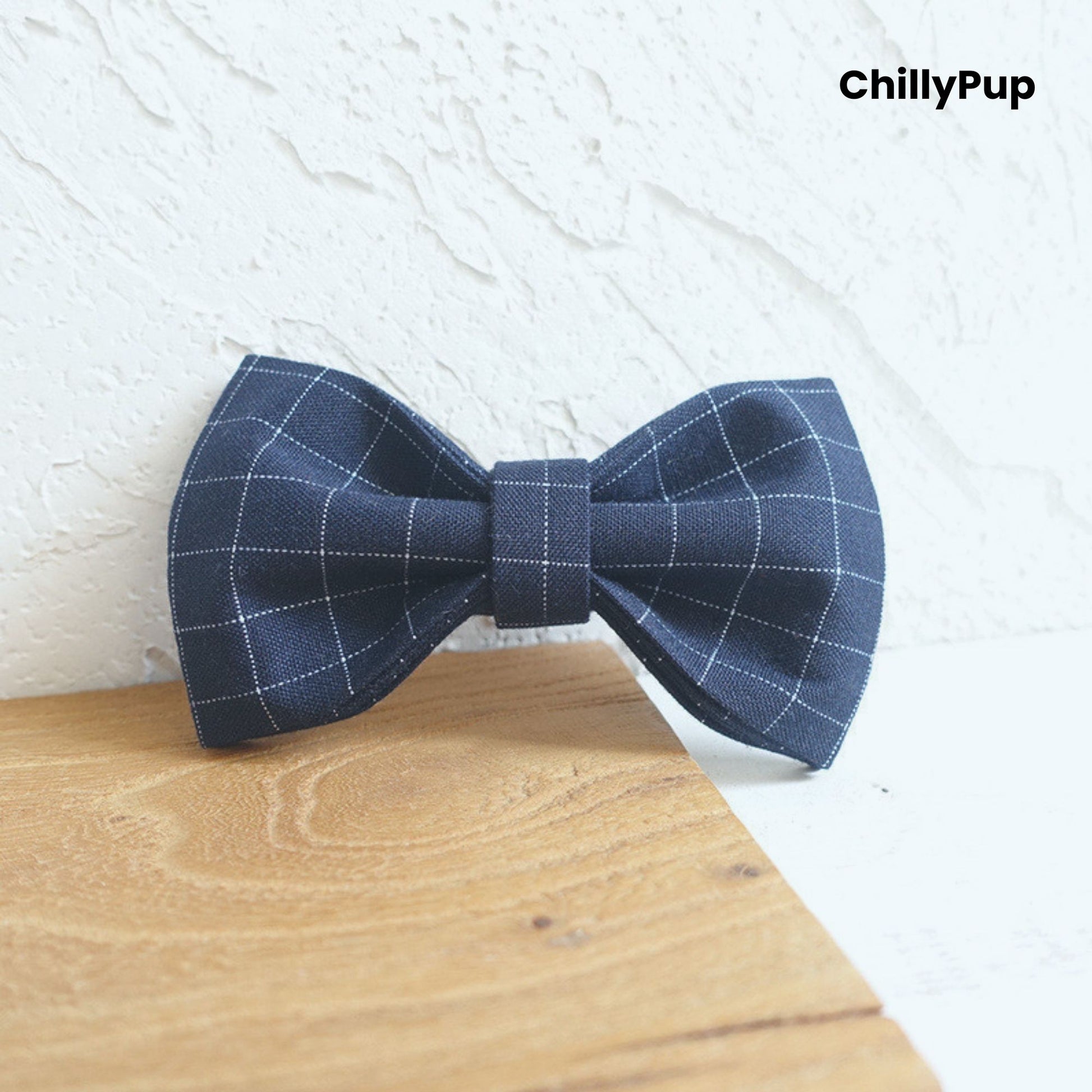 Navy check dog bow on a wooden block, branded 'ChillyPup'.