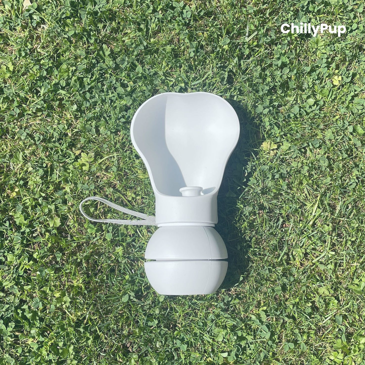 One Foldable silicone water bottle with drinking section on grass.