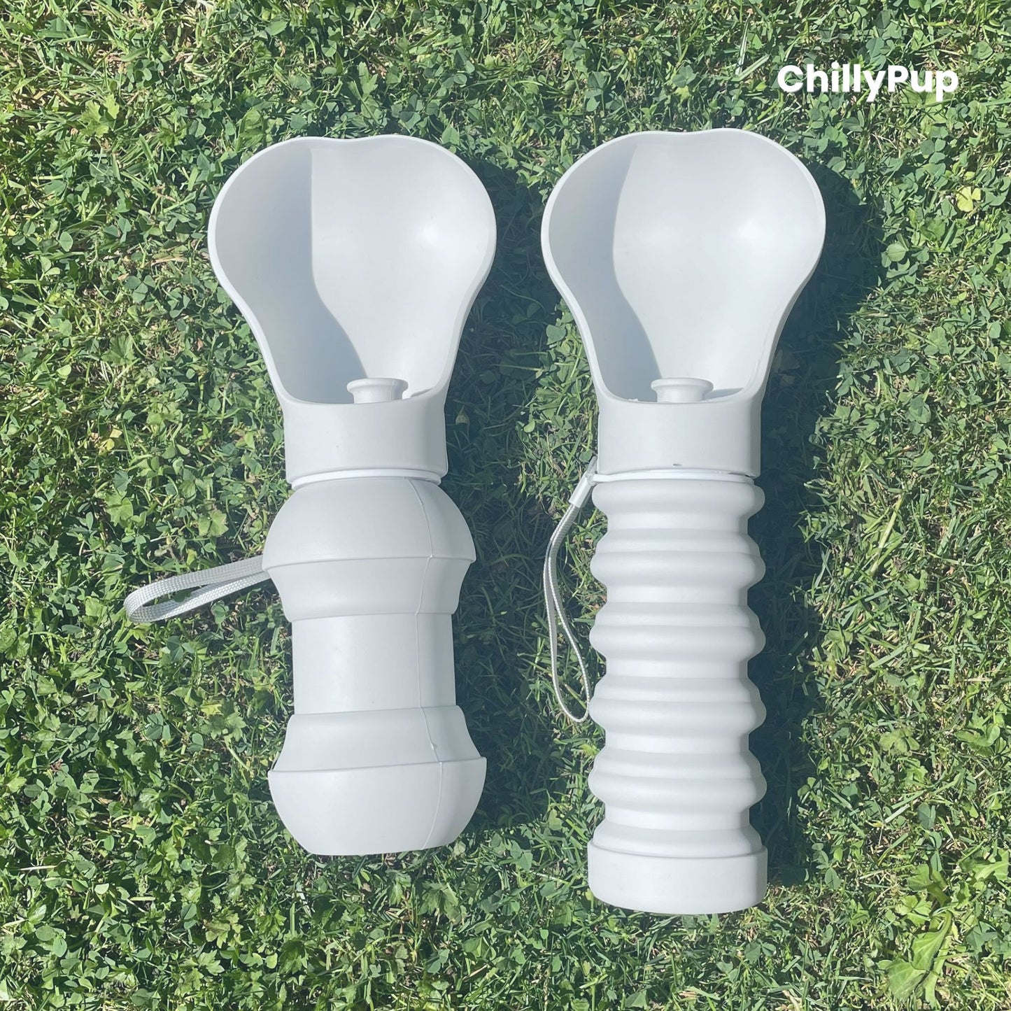 Two Foldable silicone water bottles opened up with drinking section on grass.
