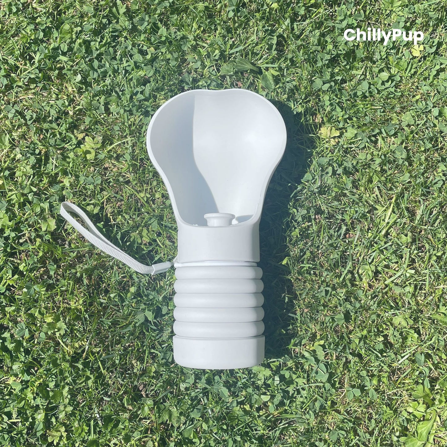 One Foldable silicone water bottle with drinking section on grass.