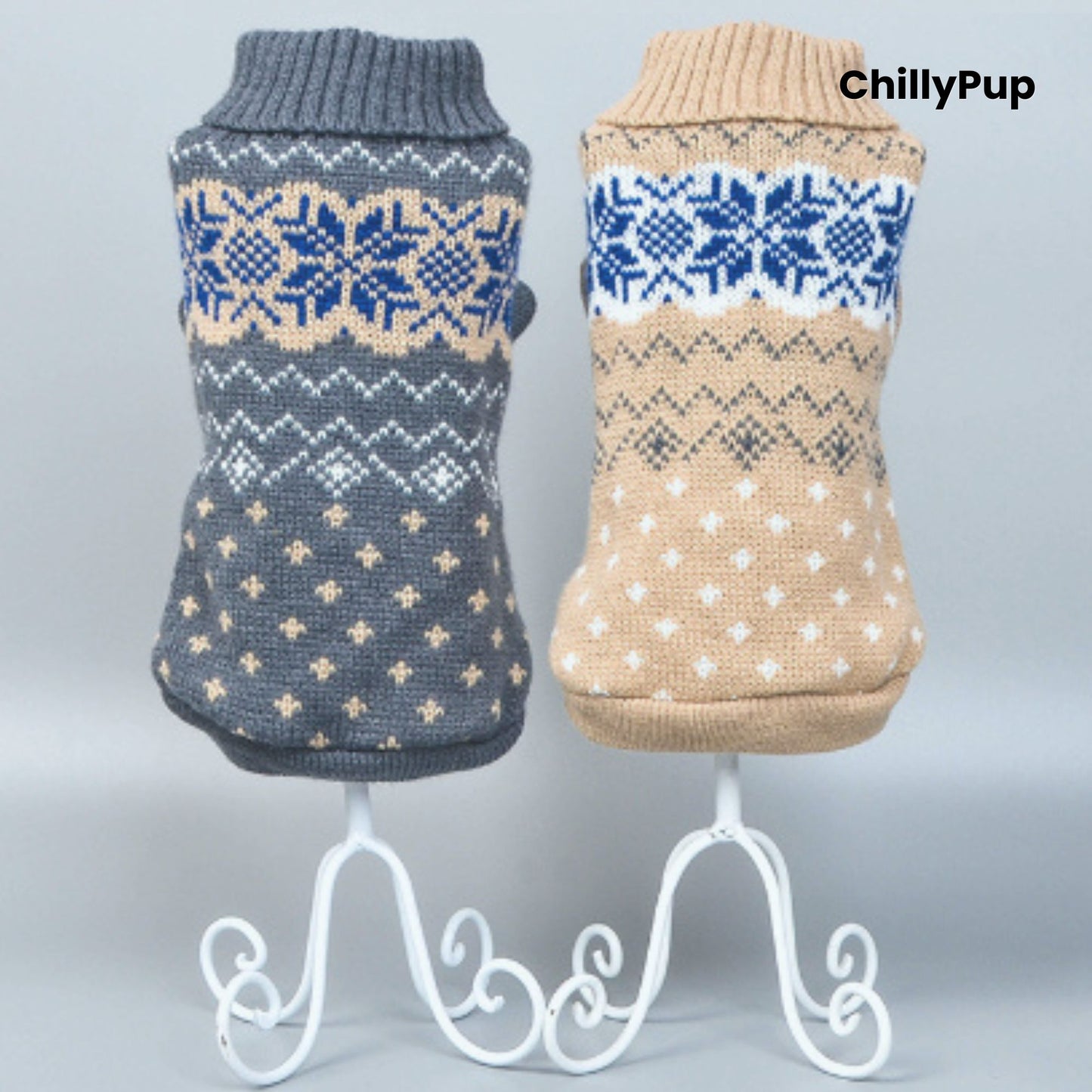 Two dog sweaters, one grey and one beige, with snowflake patterns on a white stand against a light blue background.