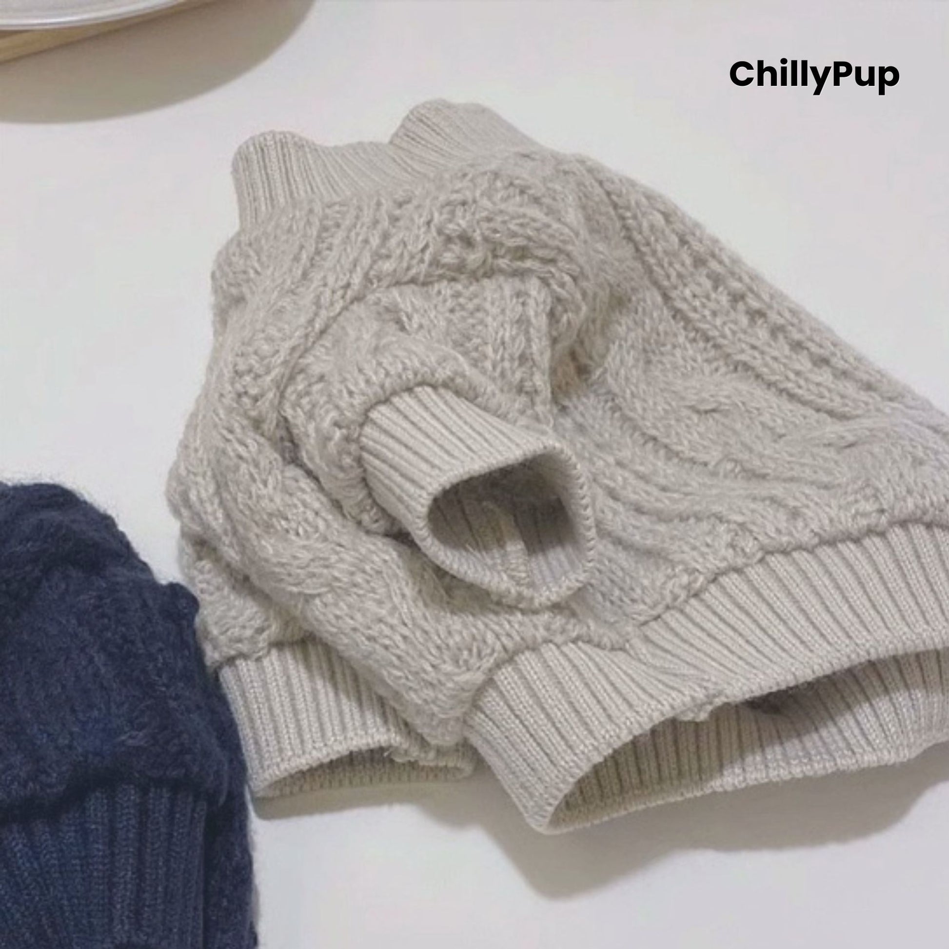 Folded beige cable knit jumper on a white surface with 'ChillyPup' branding.