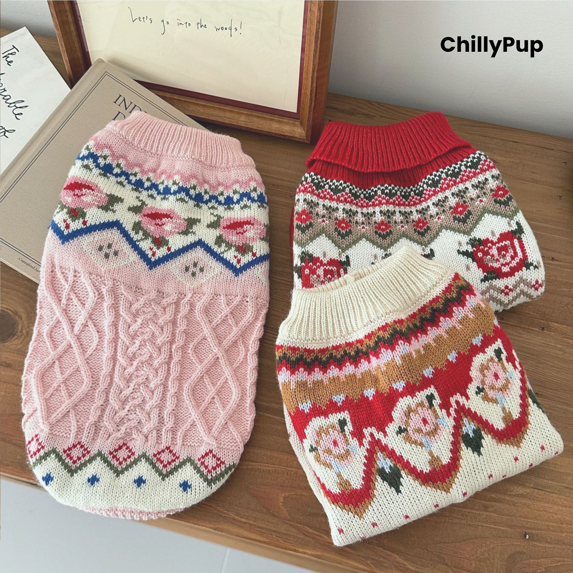 Knitted dog jumpers, one pink and one red with patterns, on a wooden surface with 'ChillyPup' branding.
