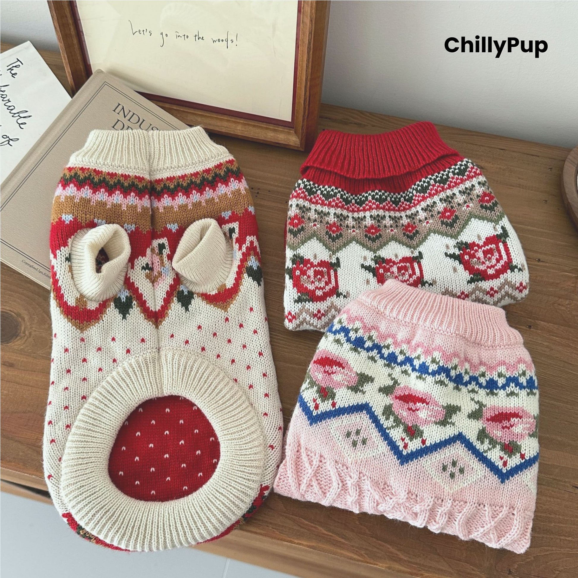 Knitted dog jumpers, one pink and one red with patterns, on a wooden surface with 'ChillyPup' branding.