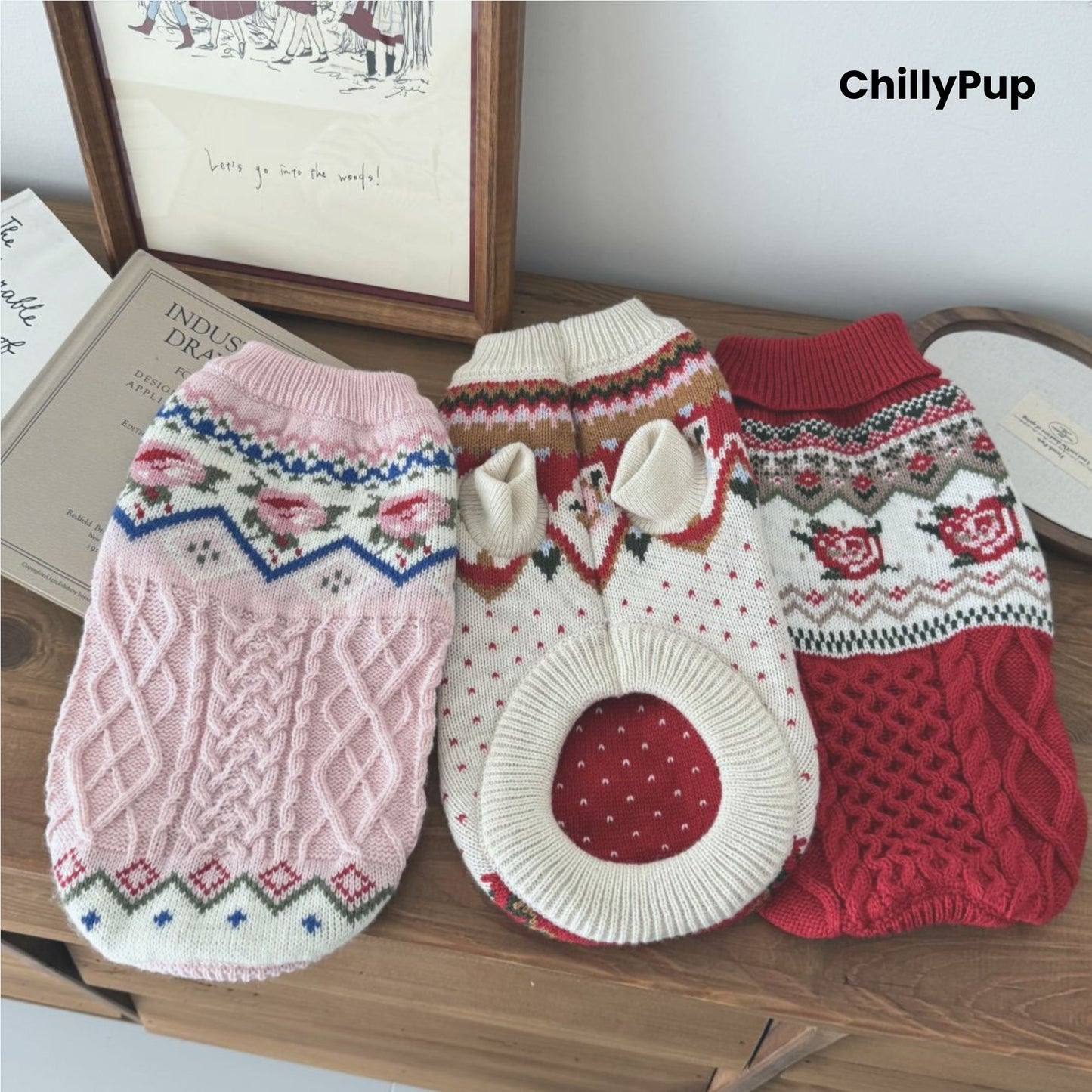 Knitted dog jumpers, one pink and one red with patterns, on a wooden surface with 'ChillyPup' branding.