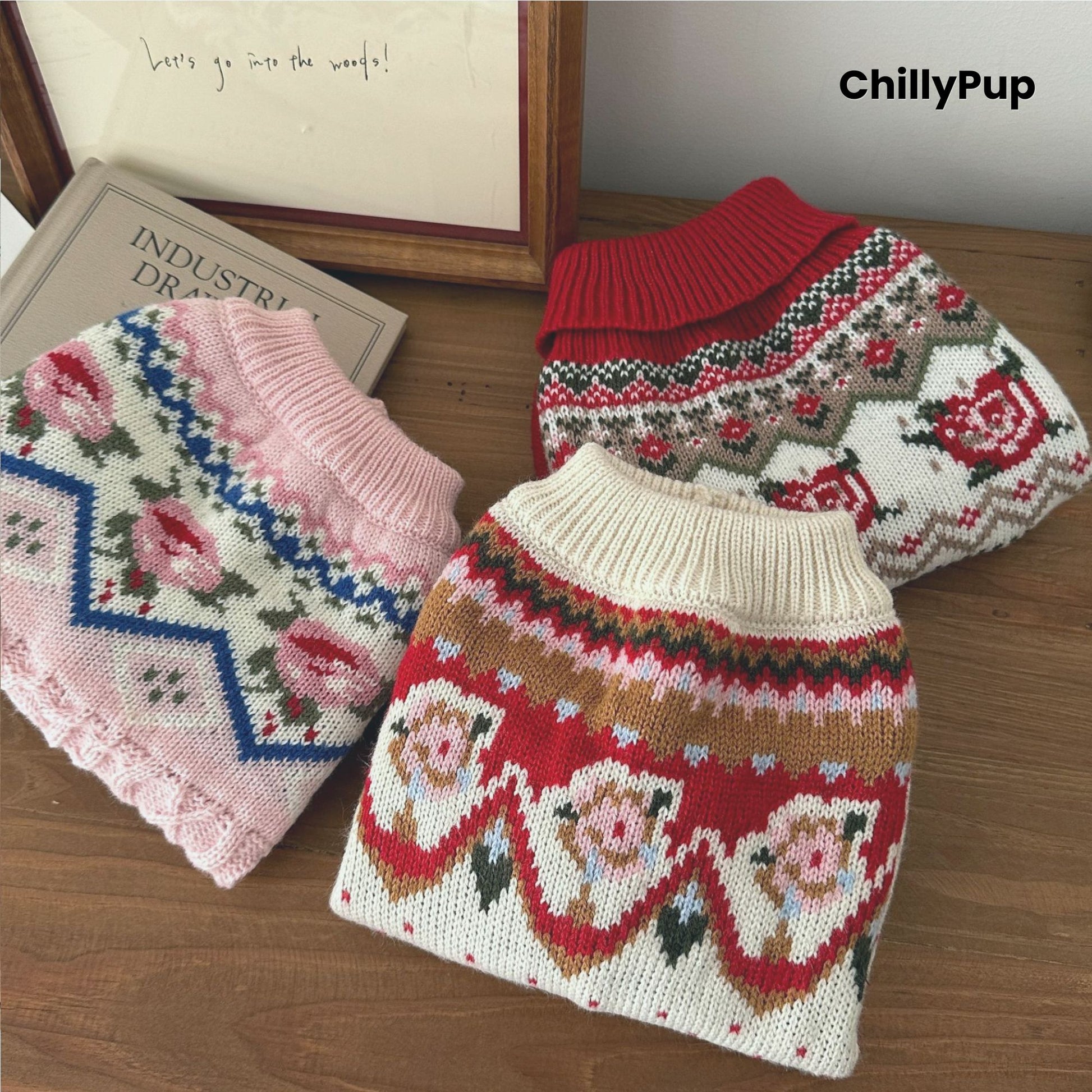 Knitted dog jumpers, one pink and one red with patterns, on a wooden surface with 'ChillyPup' branding.