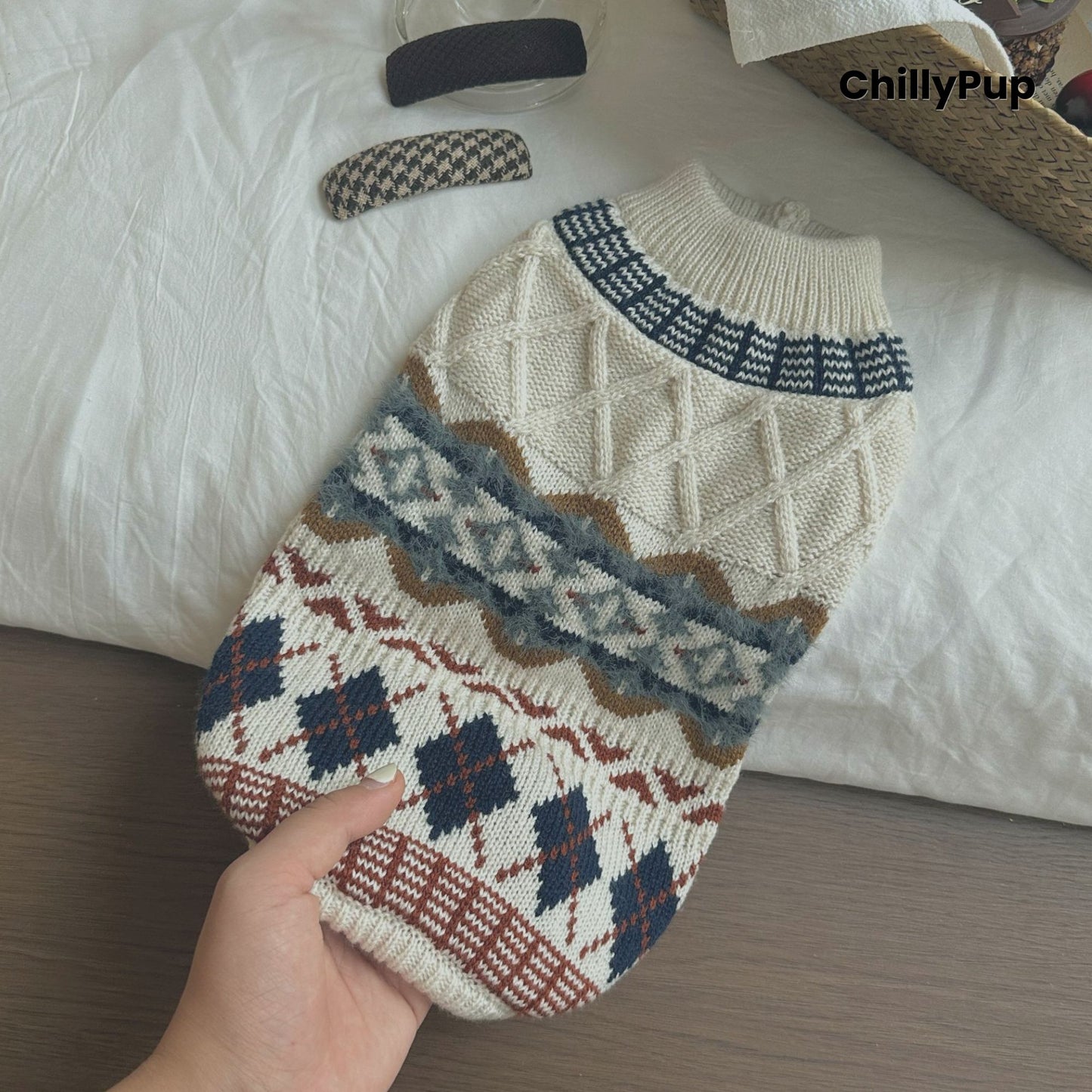 Hand holding a patterned dog sweater with 'ChillyPup' branding on a textured surface