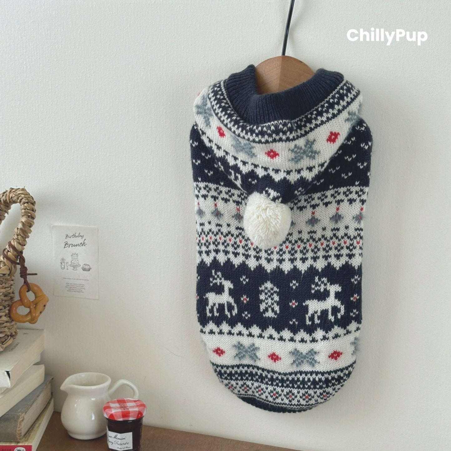 Knitted dog hoody with reindeer pattern on a wooden surface, branded 'ChillyPup'.