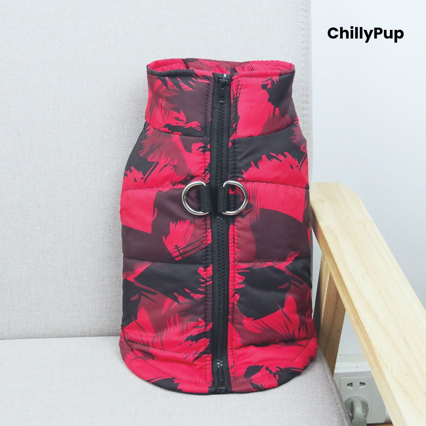 Red dog coat with a visible brand name on a light grey surface.