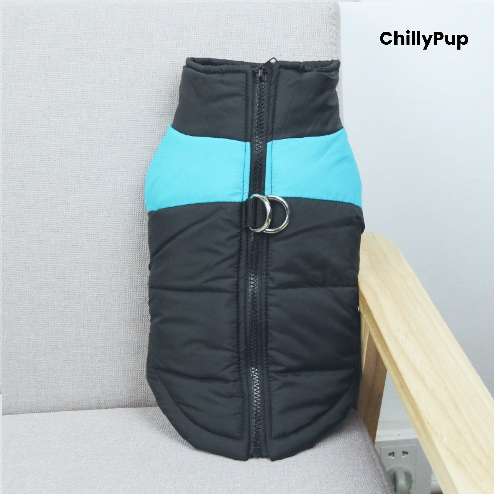 Black and blue dog coat with a visible brand name on a light grey surface.