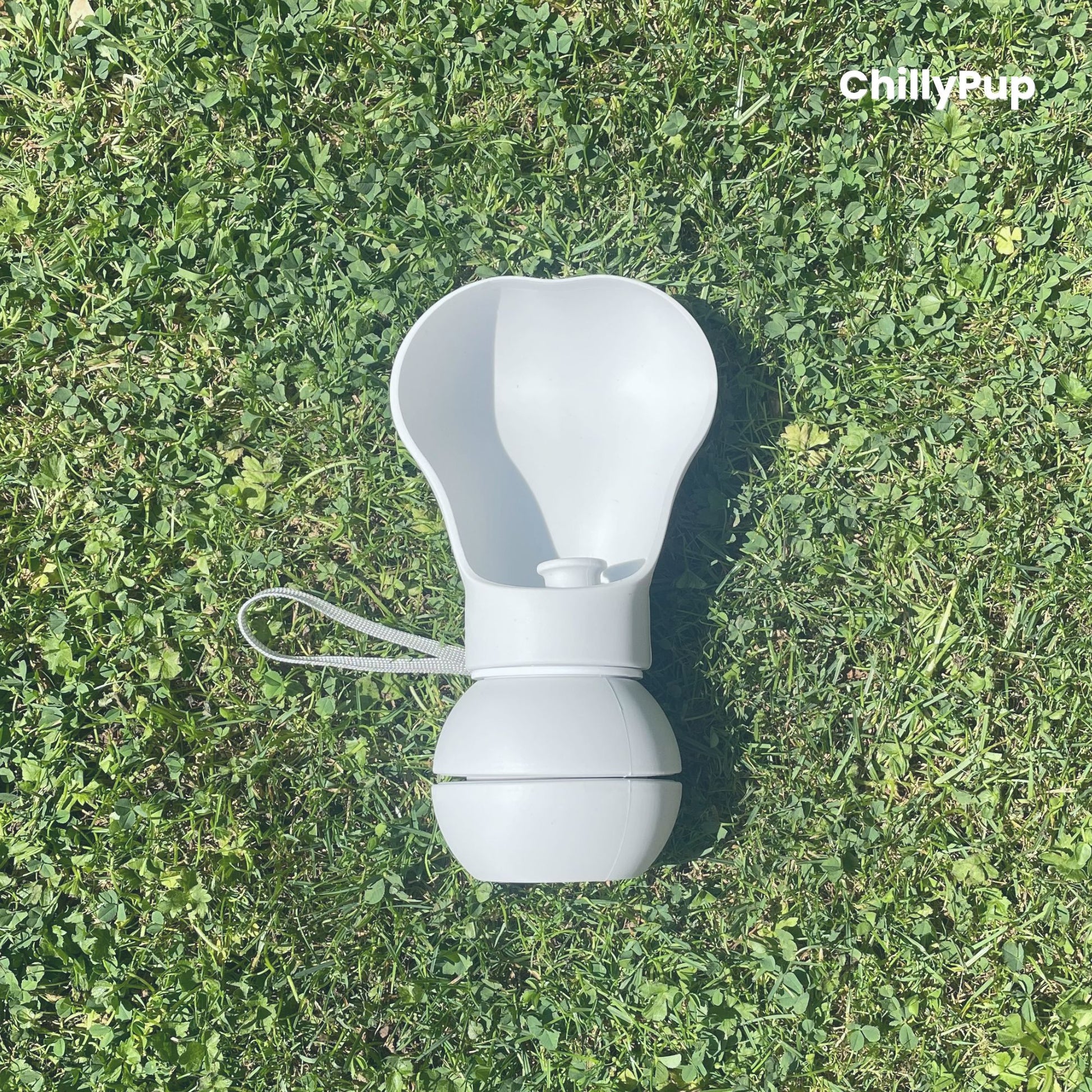 One Foldable silicone water bottle with drinking section on grass.