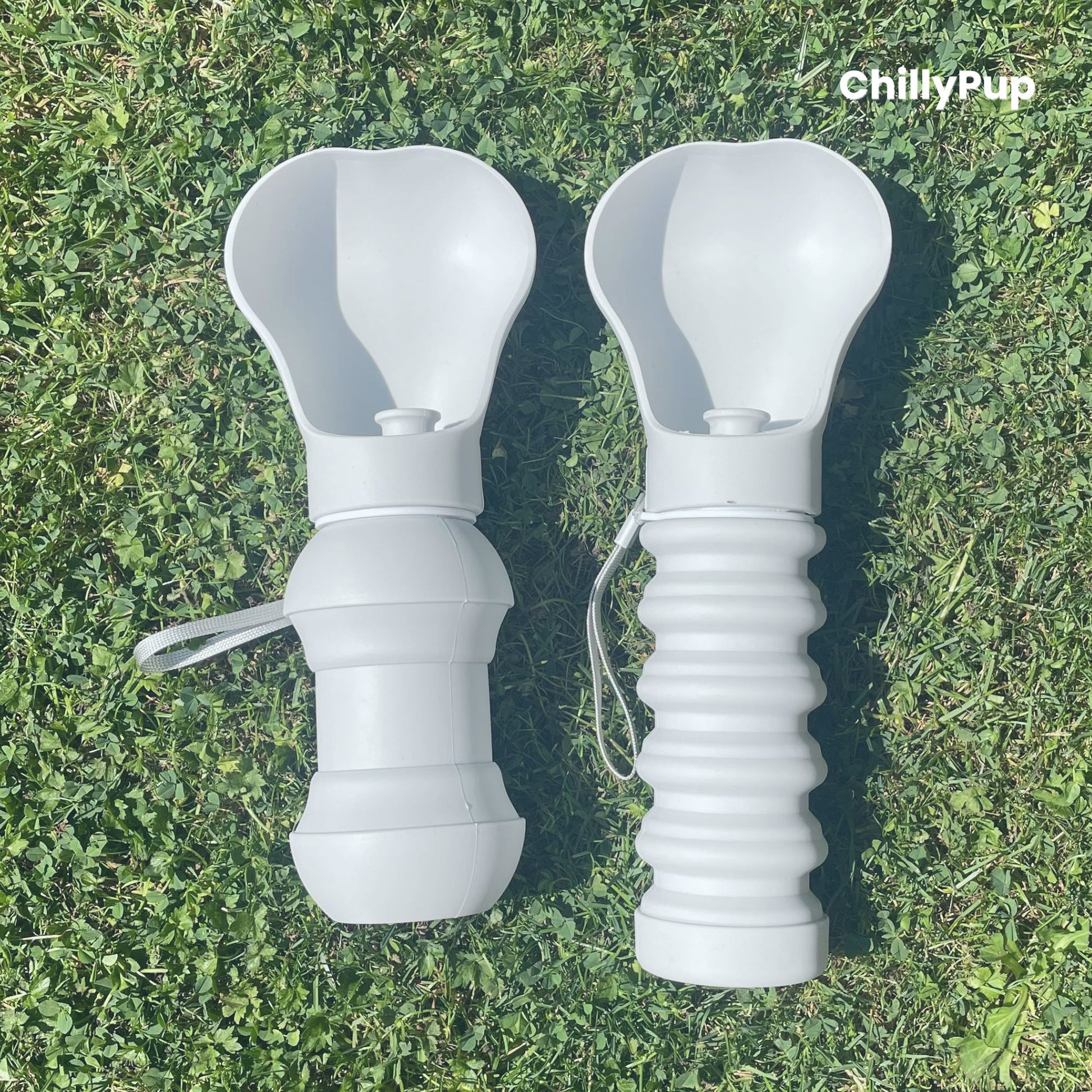 Two Foldable silicone water bottles opened up with drinking section on grass.