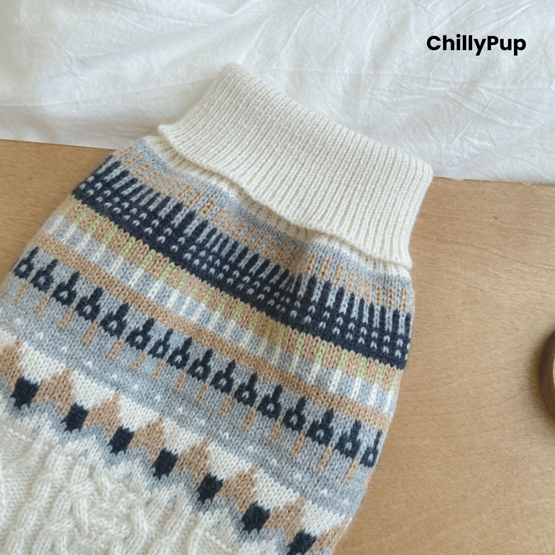 Knitted dog sweater with pattern on a wooden surface, branded 'ChillyPup'.